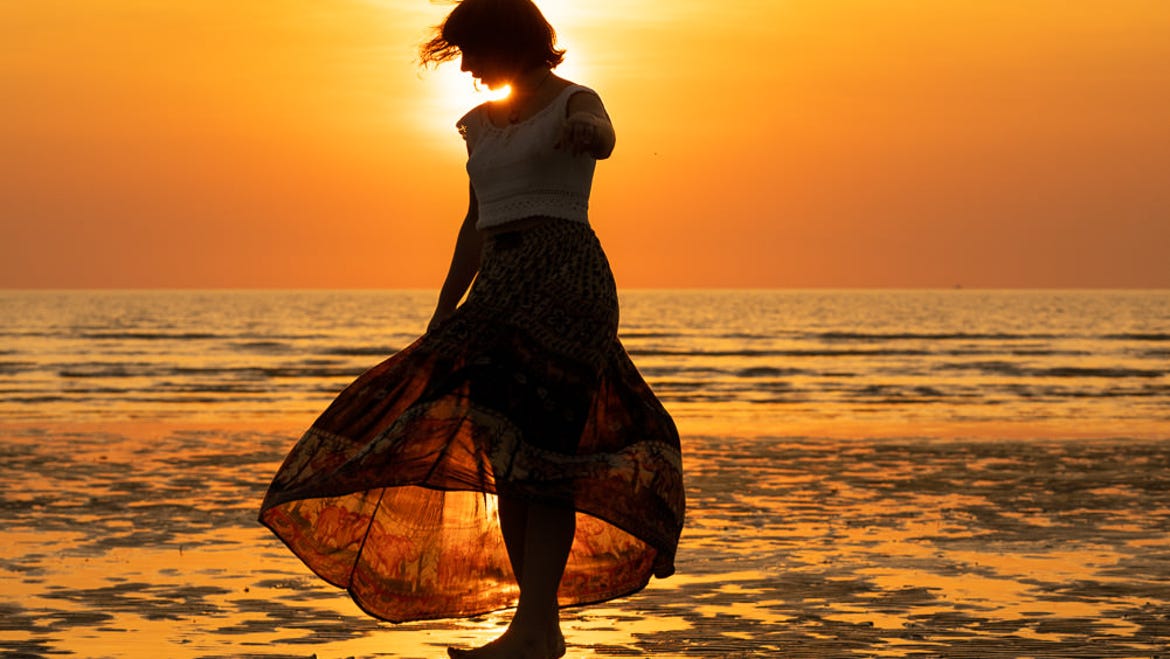 A woman in silhouette as she walks on the beach at sunset in Darwin