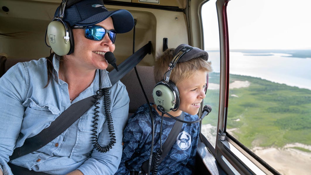 woman and young boy looking out the window at scenic views on a helifish day tour