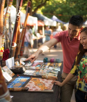Couple looking at aboriginal art at Mindil Beach Markets