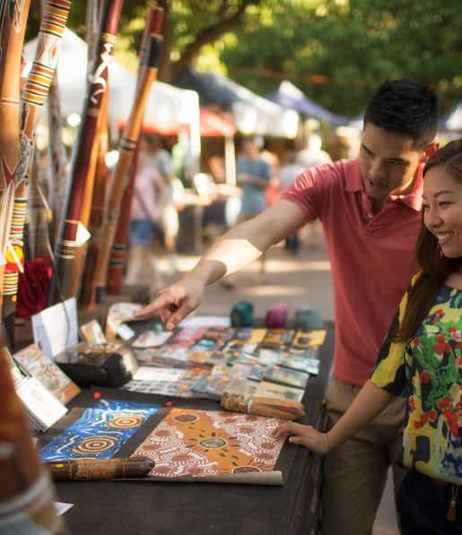 Couple looking at aboriginal art at Mindil Beach Markets