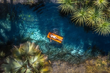 Overhead shot of woman relaxing on an inflatable mattress in the clear blue waters of Bitter Springs near Katherine
