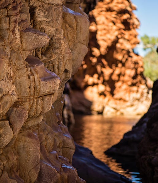 A close-up view of the rock at Redbank Gorge with the water in the background