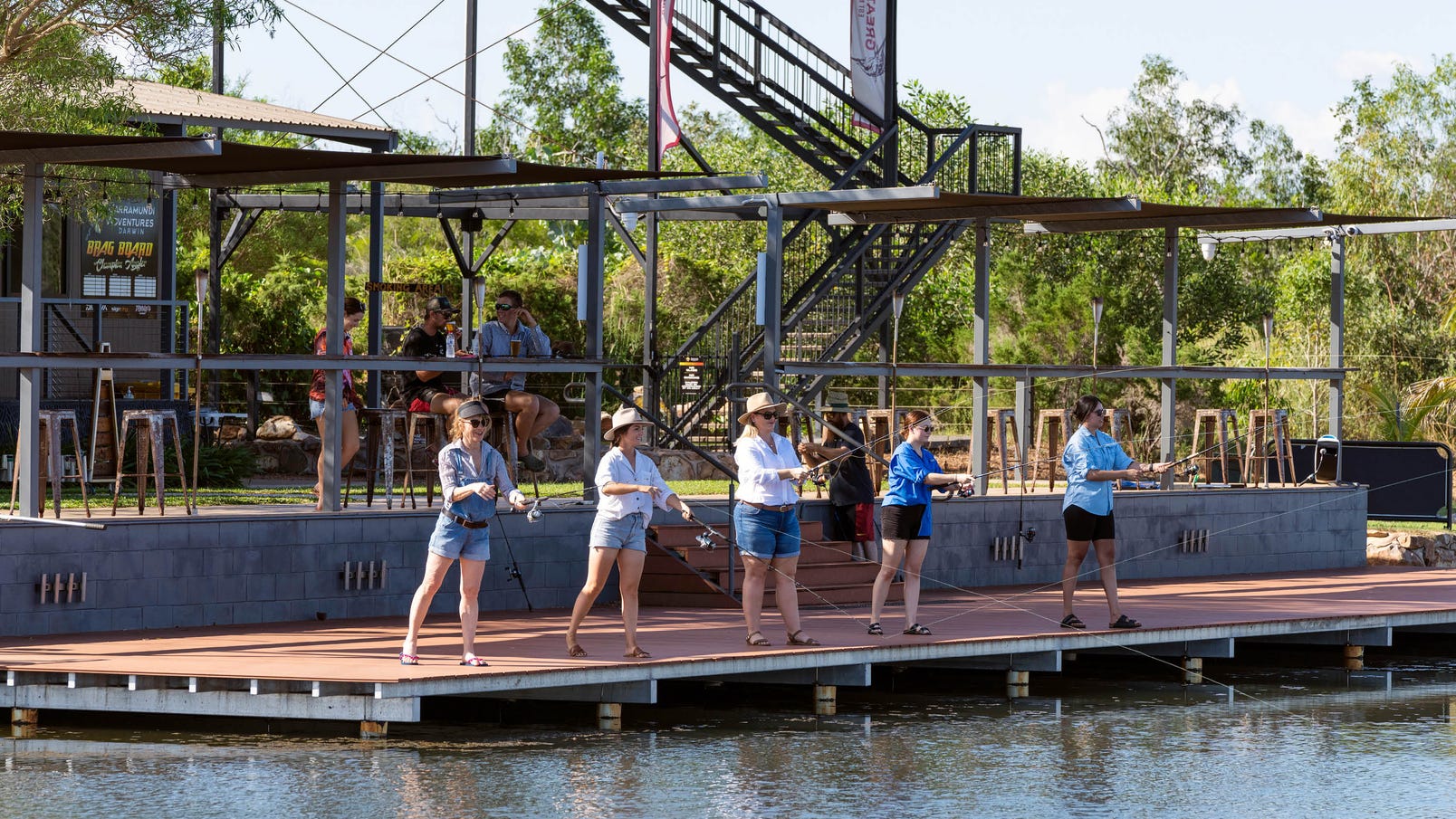five women fishing at barramundi adventures while a group enjoy refreshments behind them
