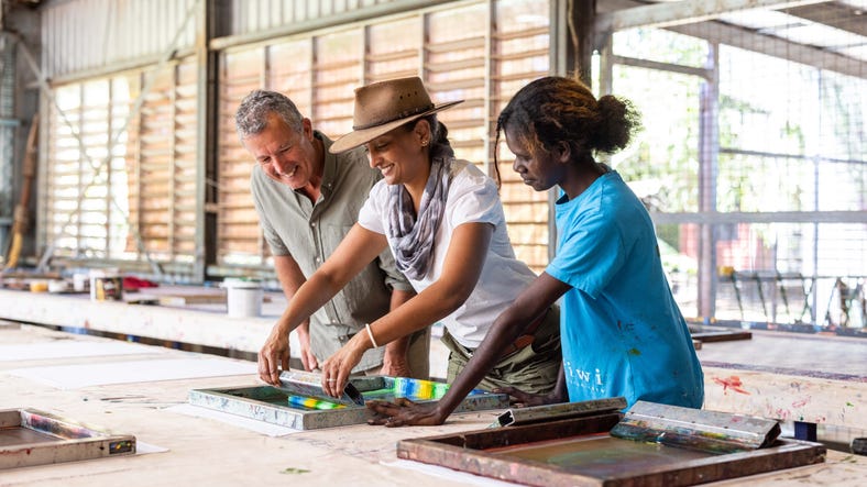 A woman showing another woman screen printing while a man watches