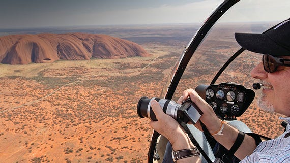 A man taking photos from a helicopter over uluru