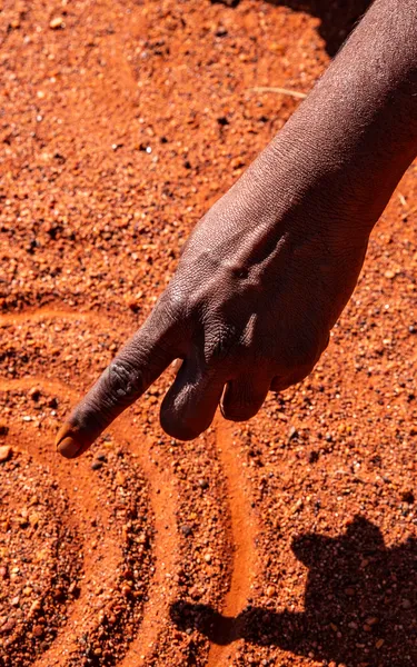 Aboriginal woman drawing on the sand
