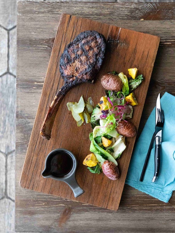 Tomahawk Steak served on a board platter at the Beachfront Hotel
