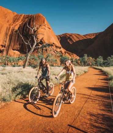 Two friends riding a bicycle together at Uluru