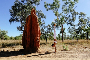 A woman doing a handstand next to a giant termite mound in Litchfield National Park near Darwin