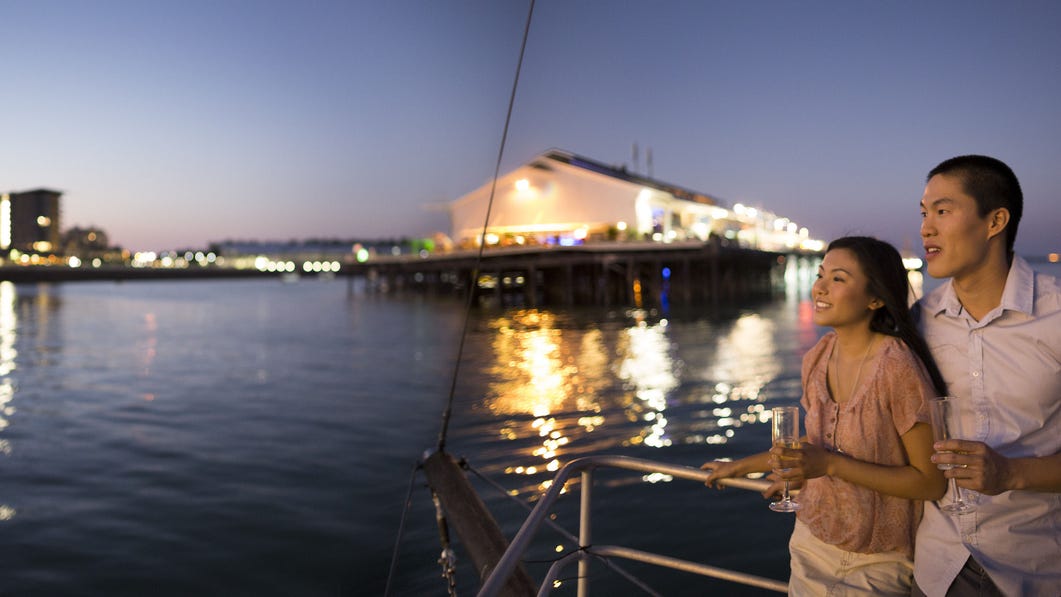 A couple on an evening cruise in Darwin Harbour with Stokes Hill Wharf in the background