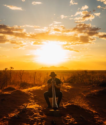 Man playing the didgeridoo at sunset