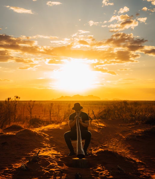 Man playing the didgeridoo at sunset
