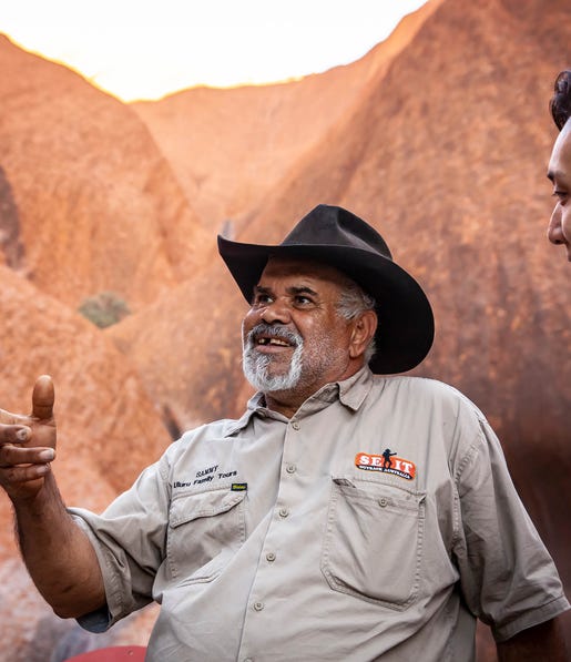 aboriginal tour guide with male tourist at uluru with s e i t tours