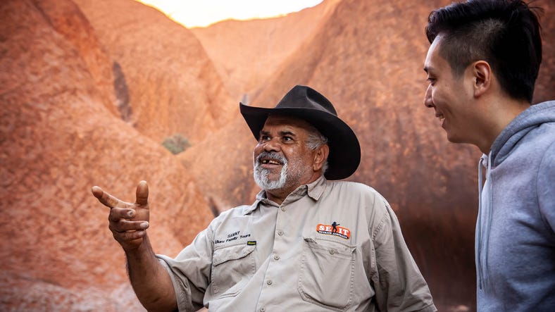 aboriginal tour guide with male tourist at uluru with s e i t tours