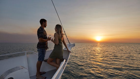 Man and woman standing on boat cruise at sunset