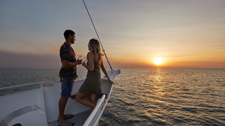 Man and woman standing on boat cruise at sunset