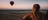 Woman looking into the distance while the sun sets on a hot air balloon in Alice Springs