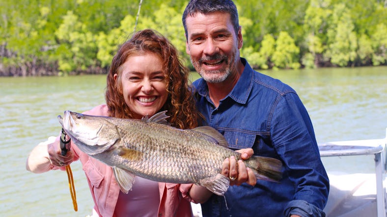A couple holding their barramundi catch