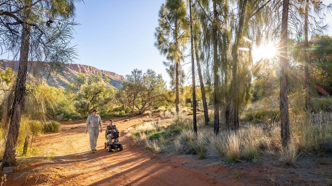 carer and person in wheelchair walking through alice springs desert park
