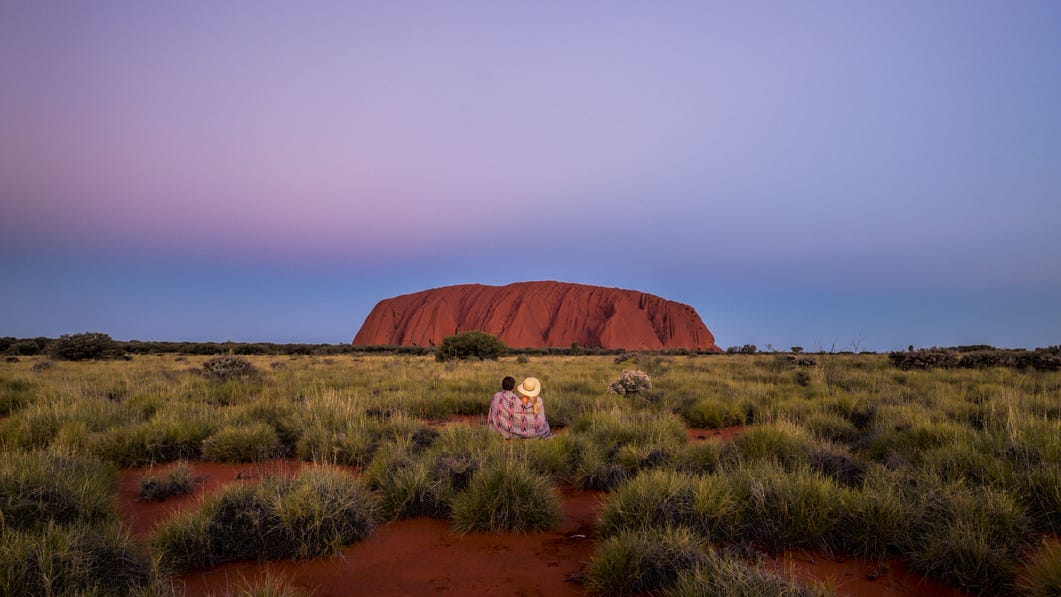 10-A couple sitting in the sand in front of Uluru