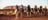 Group of visitors touring on camels with Uluru in the background