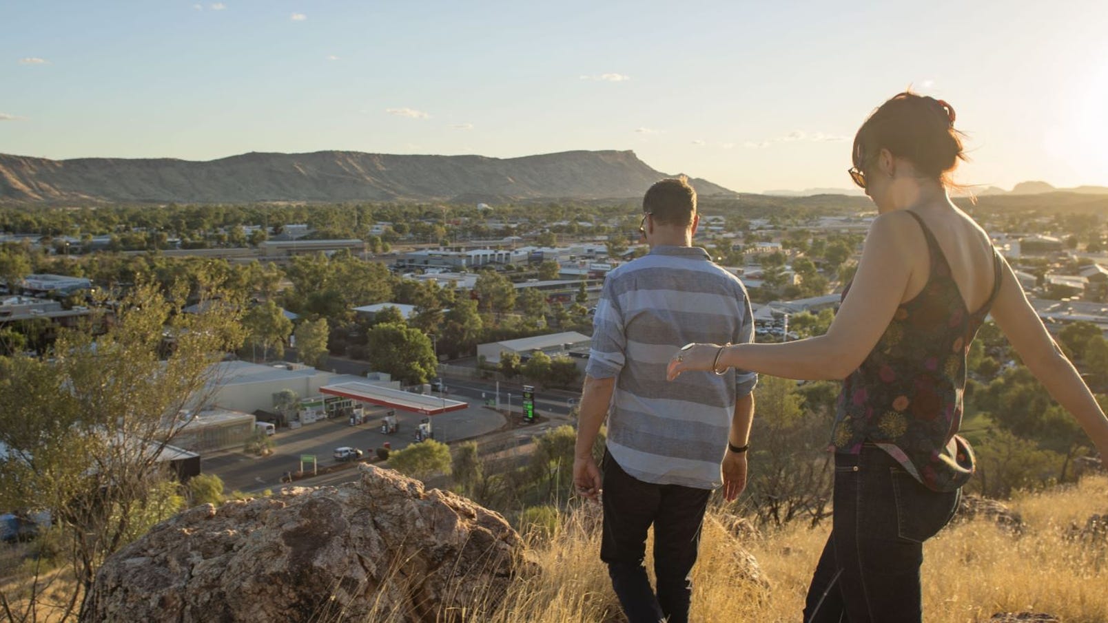 A couple walking on Anzac Hill overlooking Alice Springs at sunset