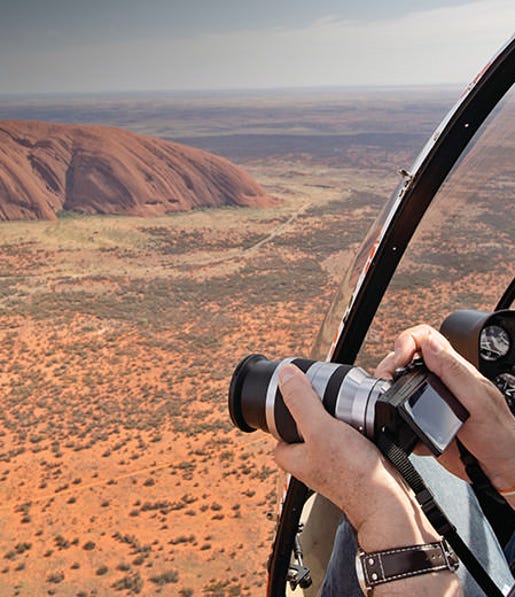 A man taking photos from a helicopter over uluru