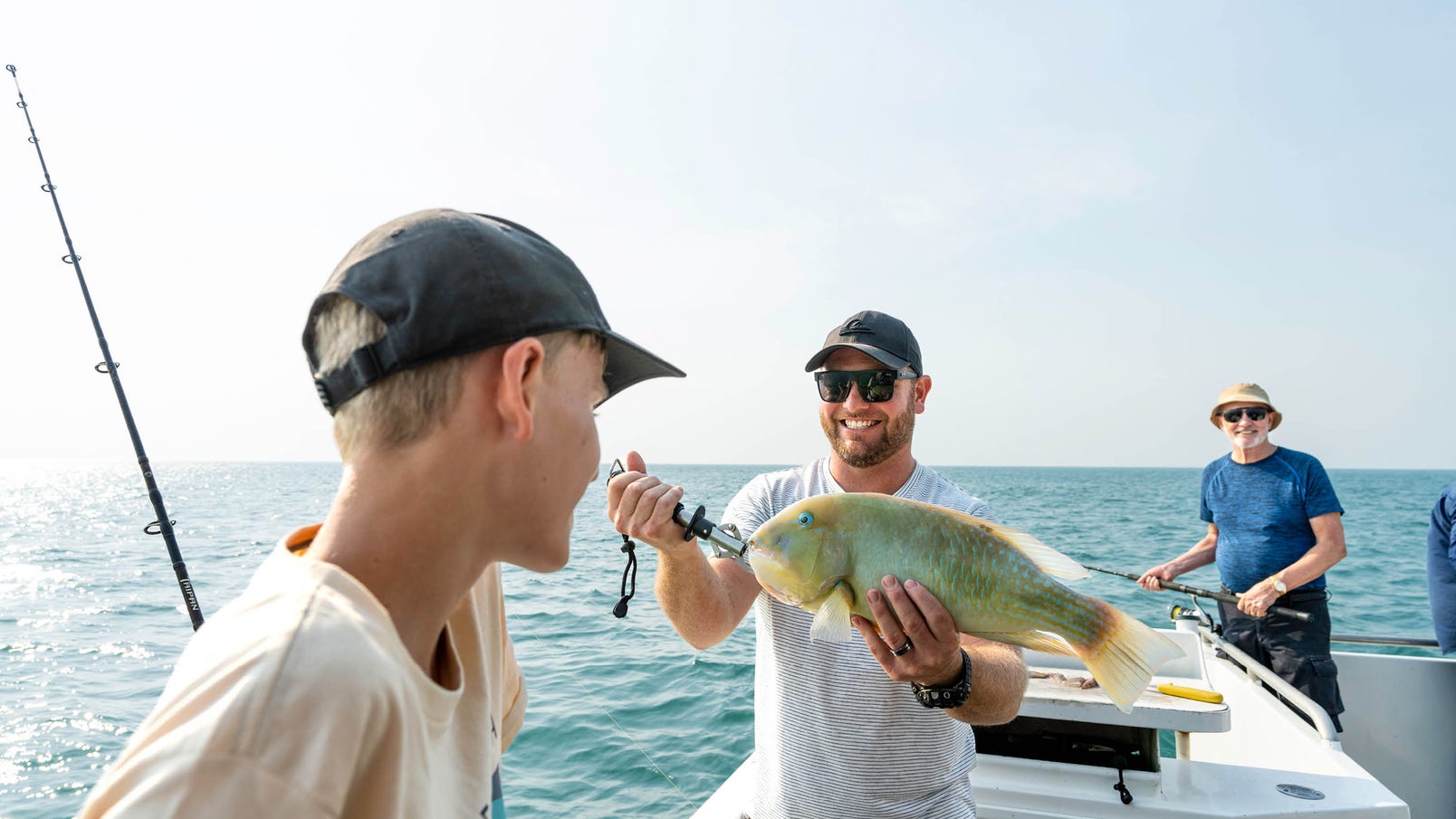 man showing young boy fish he has caught on tiwi island fishing tour
