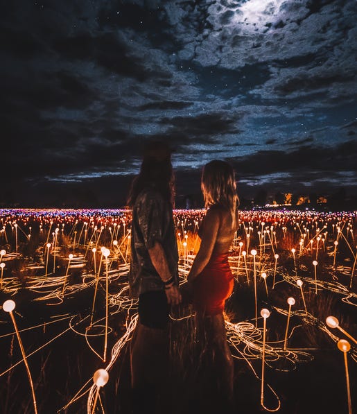 couple holding hands at field of light for the bachelor
