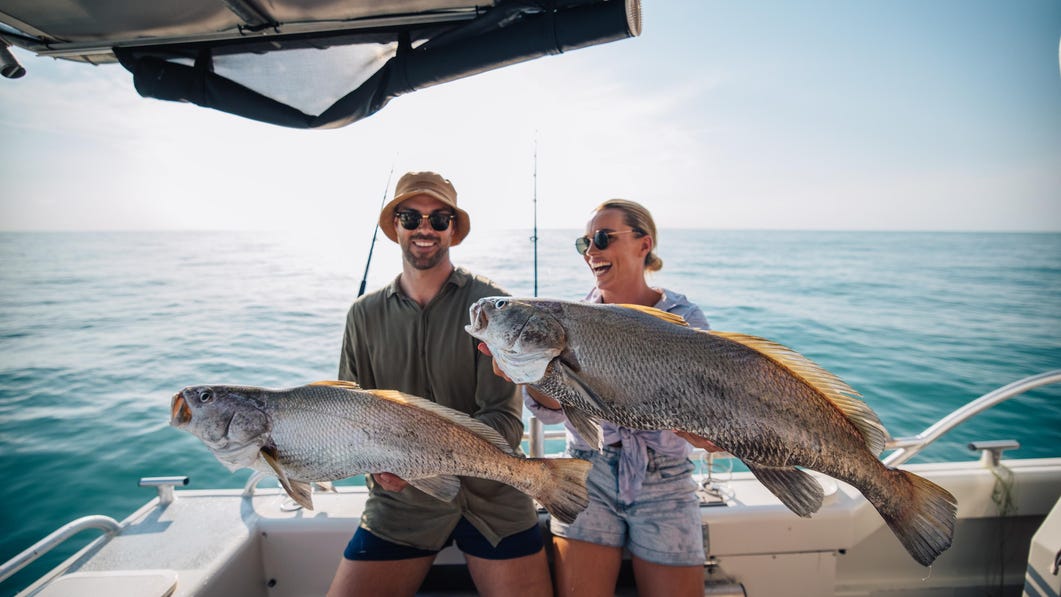 Two people holding up their big catches that they caught with yknot fishing charters in Darwin