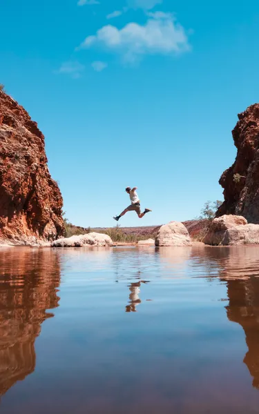 Man jumping over the water at Glen Helen Gorge