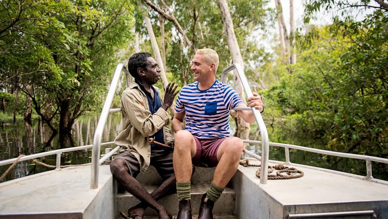 Indigenous guide speaking to tourist on billabong cruise