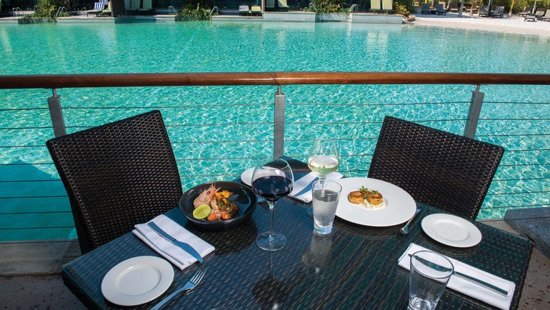 Cove Exterior Food on Table against backdrop of Lagoon Pool