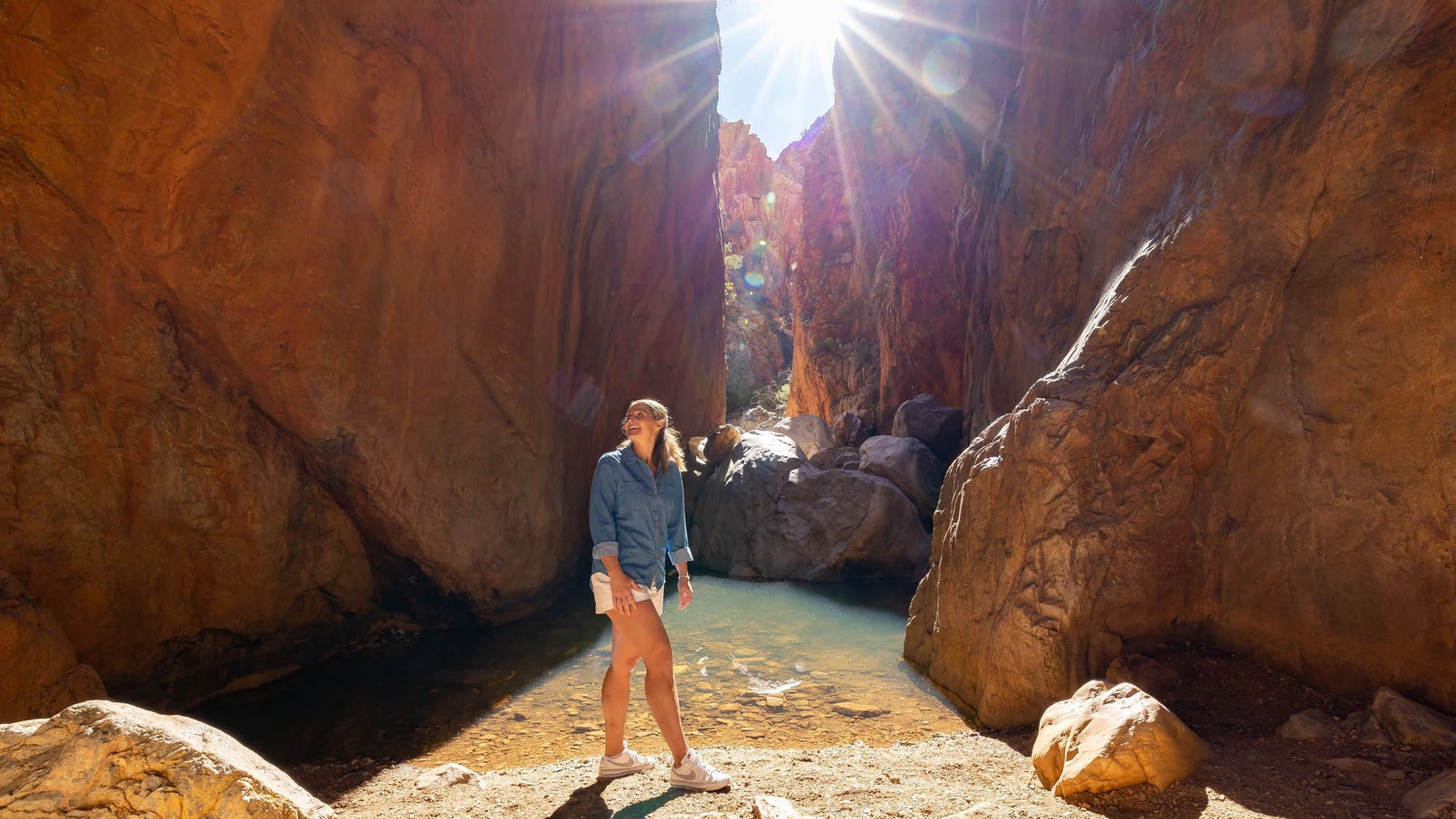 woman at the water at standley chasm with sunburst at midday