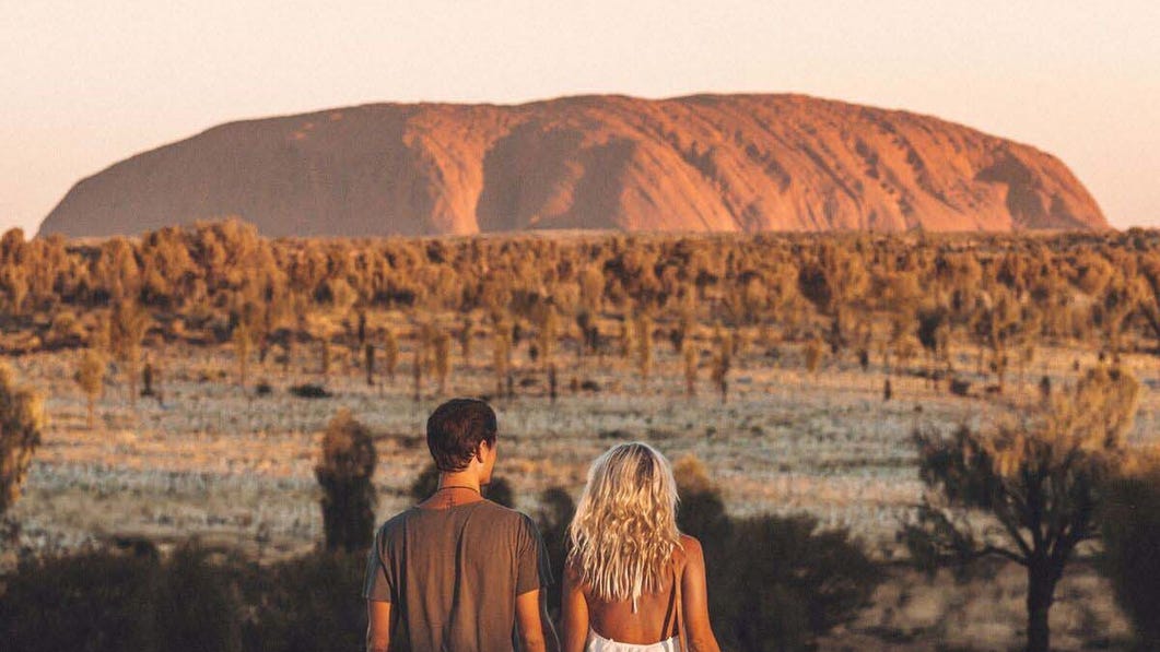 Couple holding hands looking at Uluru