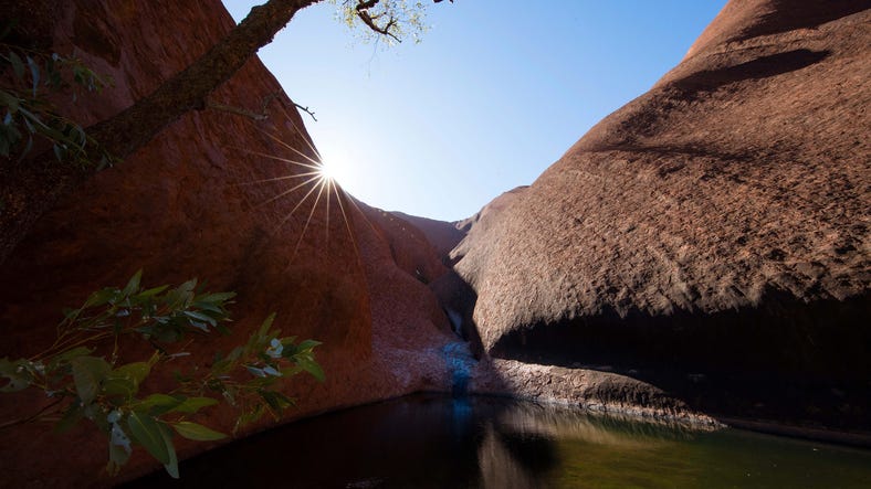 The sun shining over Mutijulu waterhole at uluru