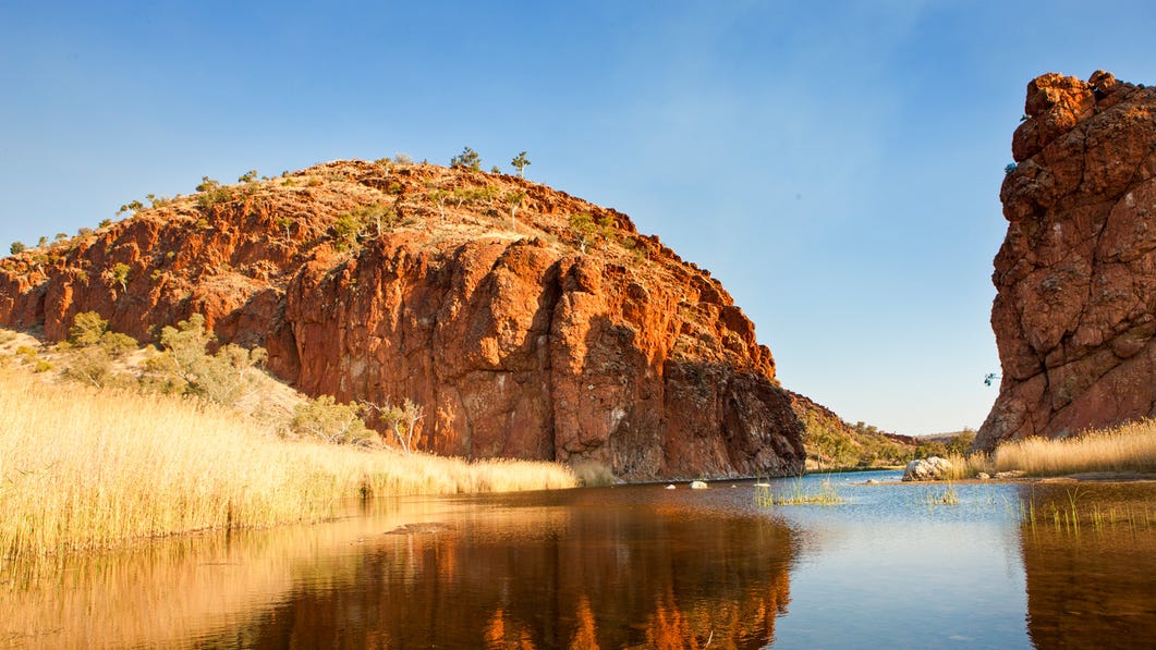 The scenic sandstone of Glen Helen Gorge and its reflection in the water