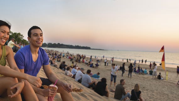 A couple sitting on the beach at Mindil Beach sunset markets