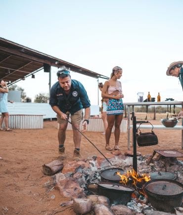 Man stoking the campfire at the earth sanctuary in Alice Springs.jpg