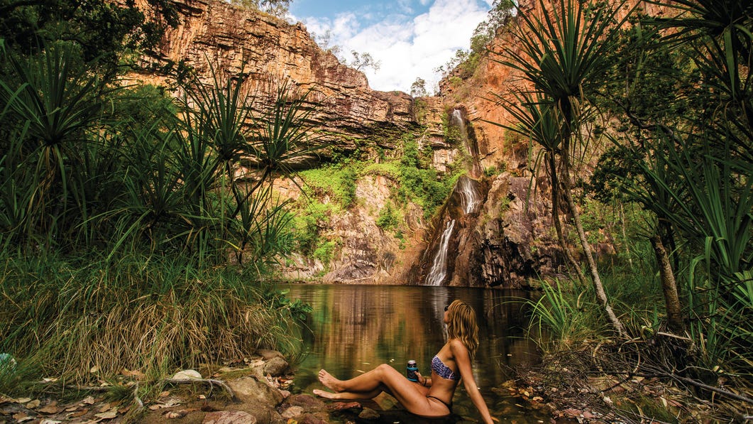 A woman sitting at the edge of the water at Sandy Creek Falls Litchfield National Park