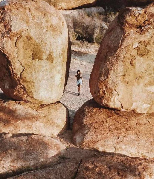 View of person walking taken between two large rocks at Karlu Karlu Devils Marbles